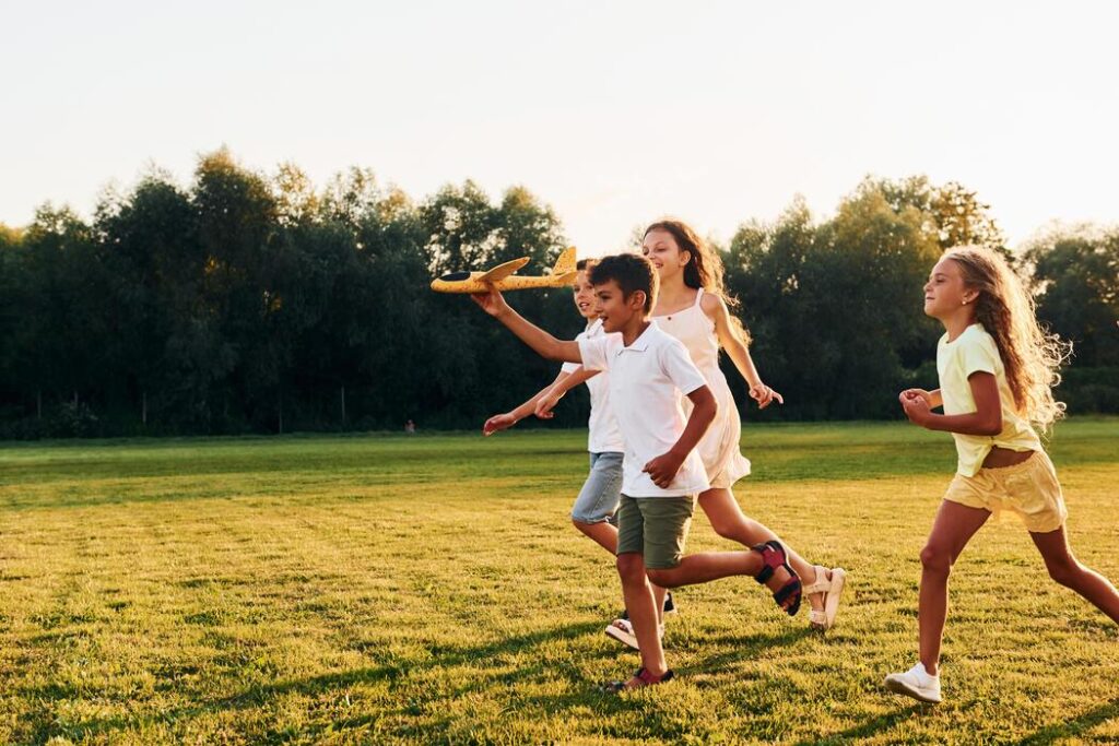 Children playing outdoors in a field, illustrating the active kids supported by pediatric foot care at CarePlus in Bellevue