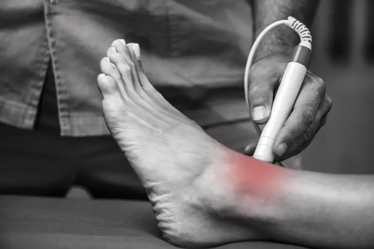 Doctor treating patient foot pain with cold laser therapy
